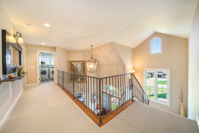 hall featuring separate washer and dryer, light colored carpet, a healthy amount of sunlight, and an inviting chandelier