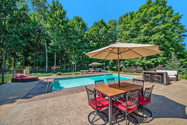 view of pool with an outdoor bar and a patio