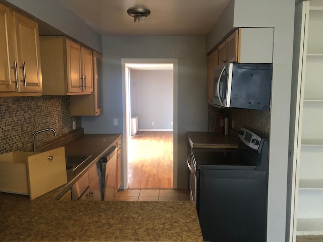 kitchen featuring light wood-type flooring, tasteful backsplash, radiator, dishwasher, and washer / dryer