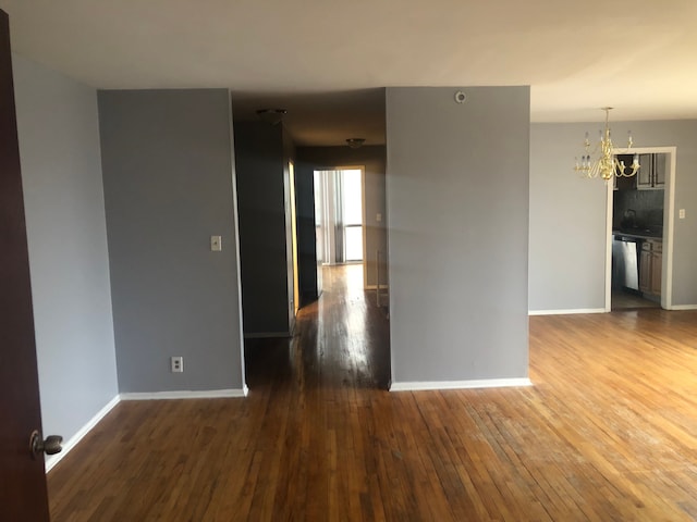 unfurnished room featuring a chandelier and dark wood-type flooring