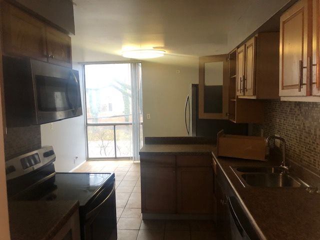 kitchen featuring sink, range with electric stovetop, backsplash, kitchen peninsula, and light tile patterned floors