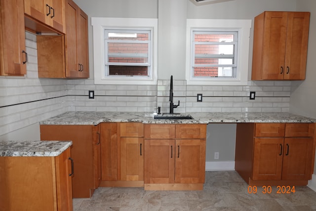 kitchen featuring tasteful backsplash, light stone countertops, and sink