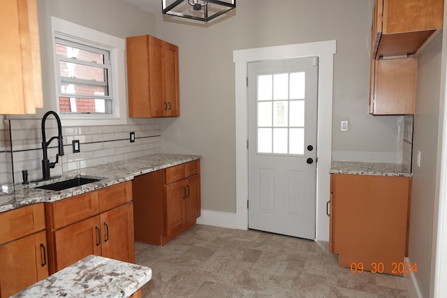 kitchen featuring decorative backsplash, light stone countertops, and sink