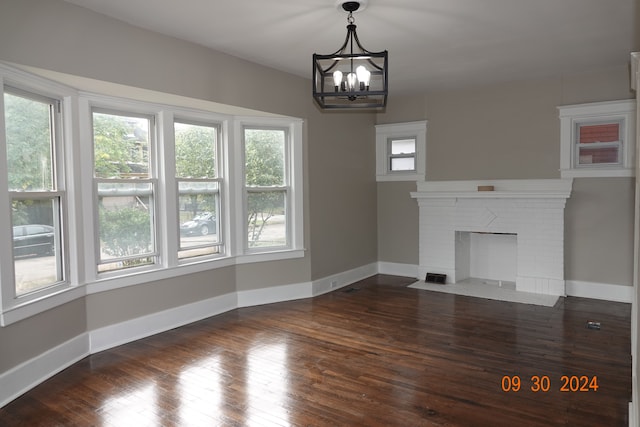 unfurnished living room with a fireplace, dark hardwood / wood-style flooring, and a notable chandelier