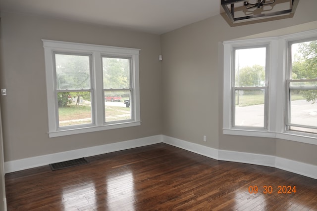 spare room with dark hardwood / wood-style flooring and a notable chandelier