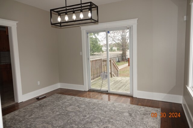 unfurnished dining area with dark hardwood / wood-style flooring and a chandelier