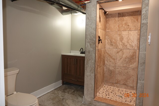 bathroom featuring a tile shower, vanity, and toilet