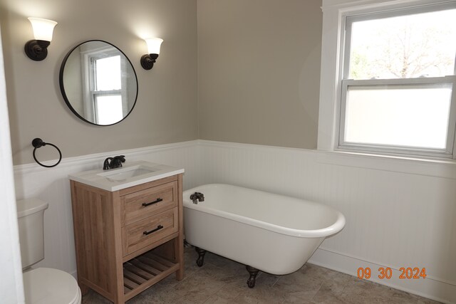 bathroom featuring a tub to relax in, tile patterned floors, vanity, and toilet