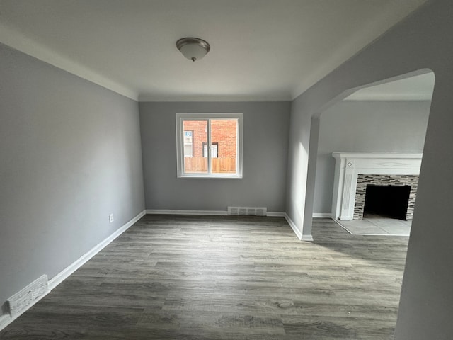 unfurnished living room with a tile fireplace and wood-type flooring