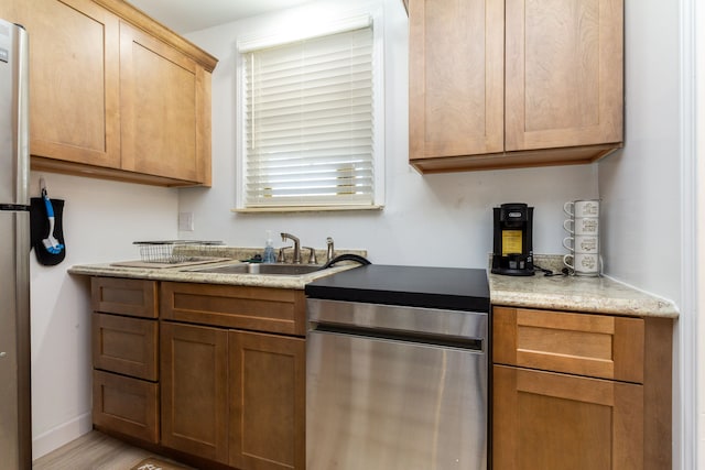 kitchen featuring stainless steel dishwasher, light wood-type flooring, and sink