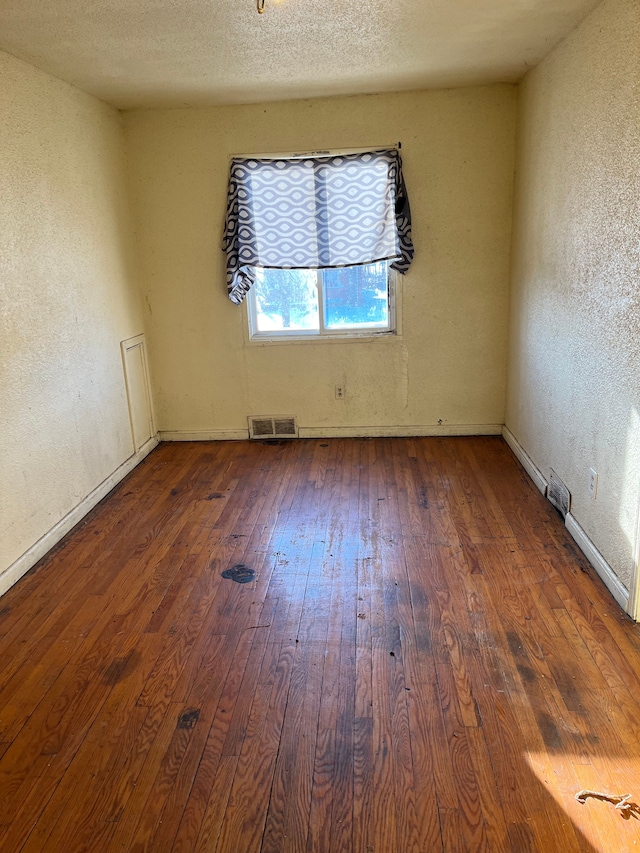 empty room featuring dark wood-type flooring and a textured ceiling