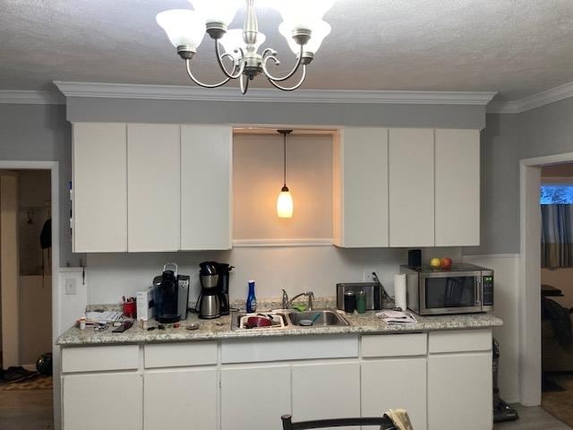 kitchen featuring a notable chandelier, white cabinetry, and sink