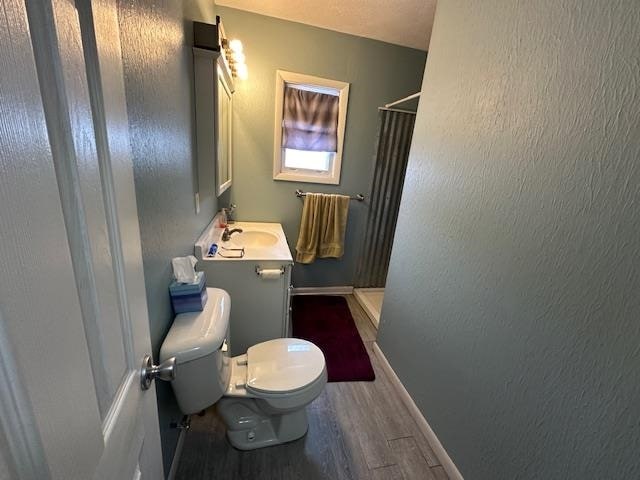 bathroom with hardwood / wood-style flooring, vanity, curtained shower, and toilet