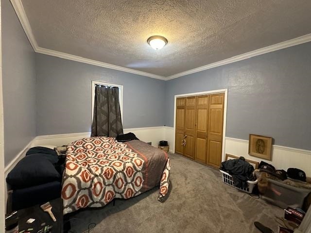 bedroom featuring carpet flooring, a textured ceiling, a closet, and ornamental molding