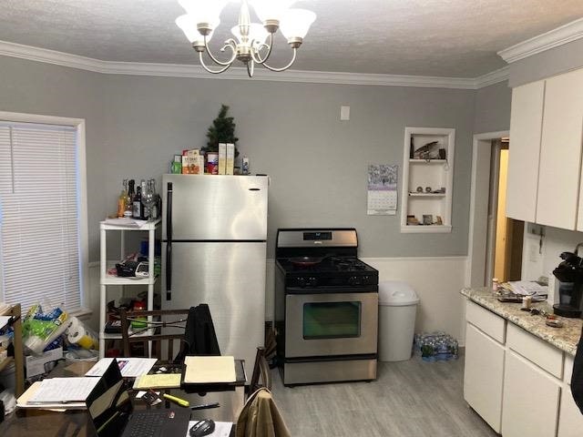 kitchen featuring white cabinetry, a notable chandelier, crown molding, light hardwood / wood-style floors, and appliances with stainless steel finishes