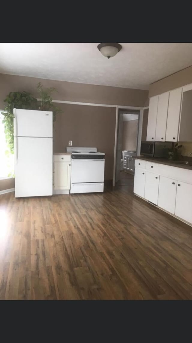 kitchen with white cabinets, dark hardwood / wood-style floors, and white appliances