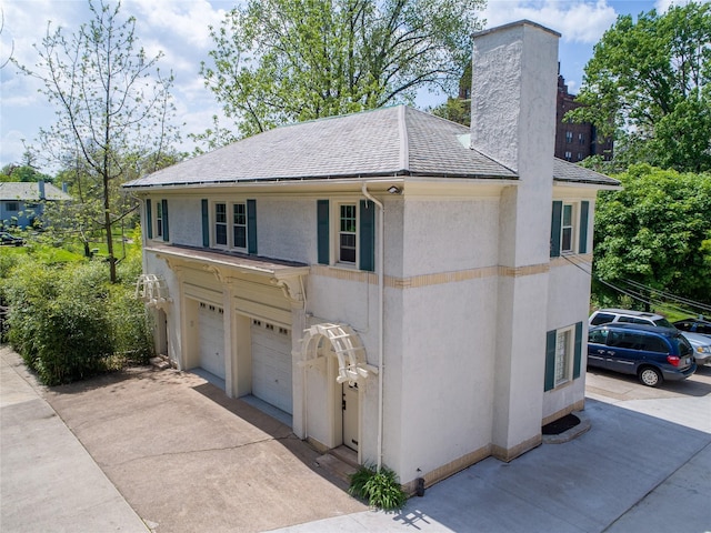 70 W Boston Blvd, Detroit, MI 48202 - view of front facade with a chimney, stucco siding, a garage, concrete driveway, and roof with shingles