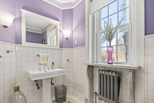 bathroom featuring radiator heating unit, crown molding, and tile walls