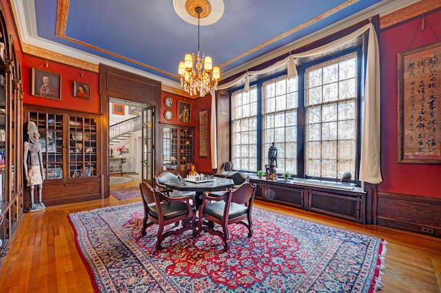 dining space with a chandelier, wood-type flooring, and crown molding