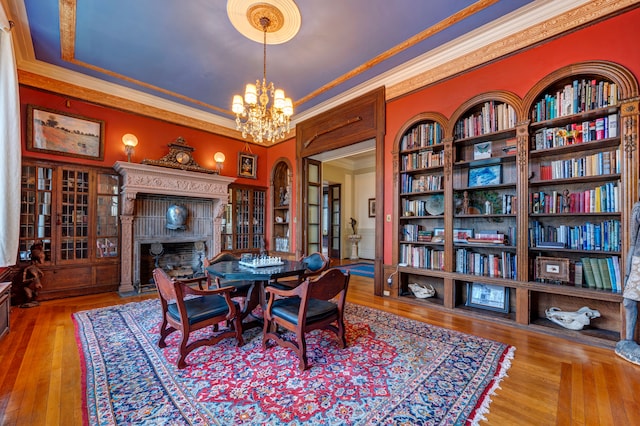 dining room featuring built in shelves, wood-type flooring, ornamental molding, and a chandelier