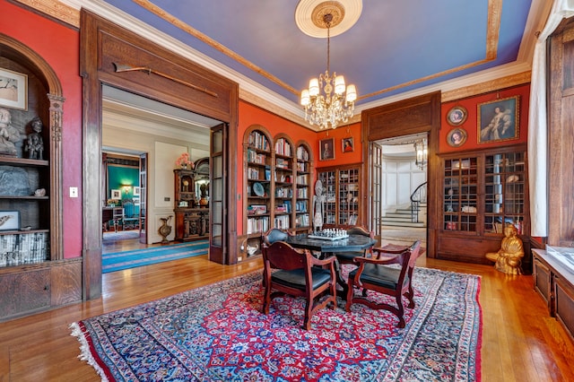 dining area featuring built in shelves, light wood-type flooring, ornamental molding, and a chandelier