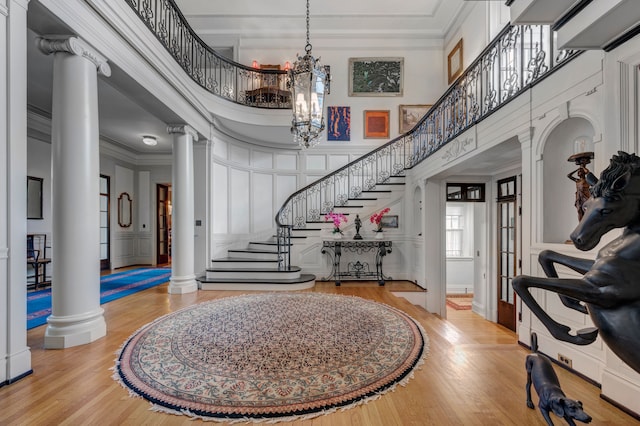 entrance foyer with a high ceiling, decorative columns, hardwood / wood-style flooring, and crown molding