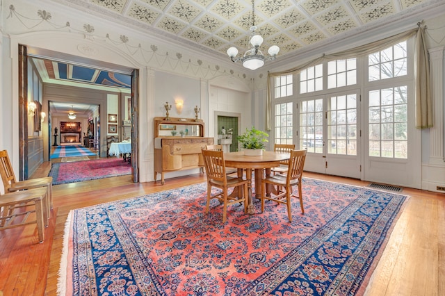 dining area with a chandelier, ornamental molding, a towering ceiling, and light hardwood / wood-style flooring