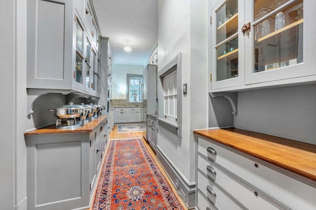 kitchen featuring butcher block countertops, white cabinetry, and crown molding