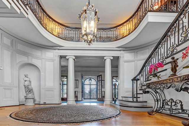 foyer with ornate columns, ornamental molding, and a high ceiling