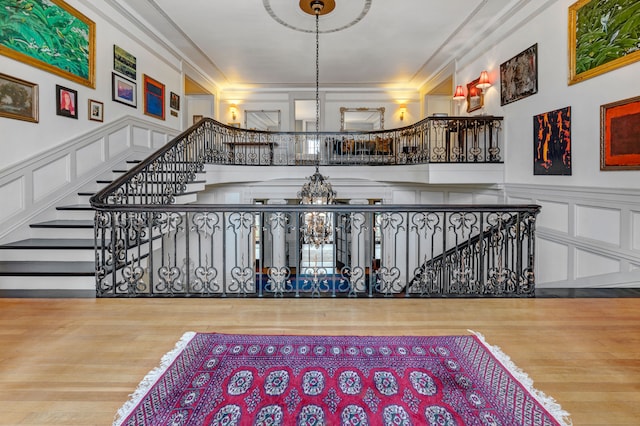 staircase featuring an inviting chandelier, wood-type flooring, and ornamental molding