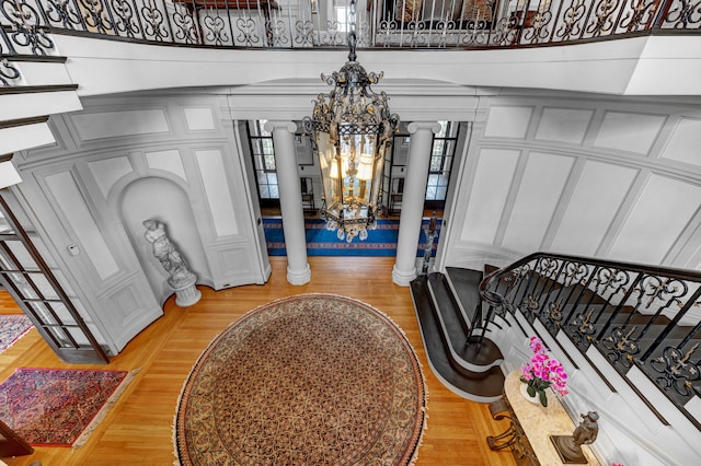 entrance foyer featuring a notable chandelier, wood-type flooring, and ornate columns