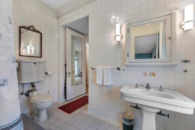 bathroom featuring tile patterned flooring, toilet, and tile walls