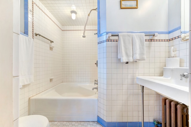 bathroom with toilet, tile walls, radiator, and tiled shower / bath