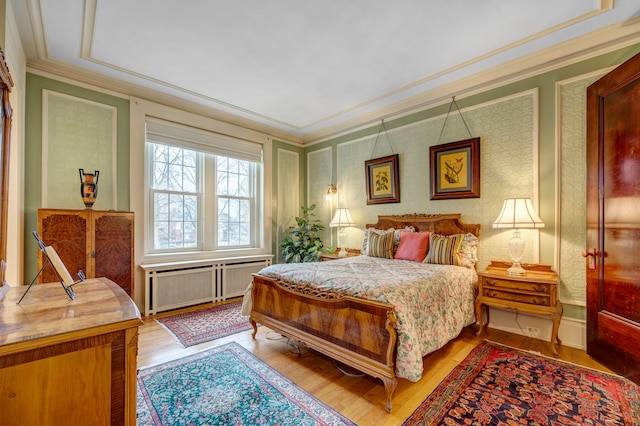 bedroom with hardwood / wood-style floors, ornamental molding, and radiator