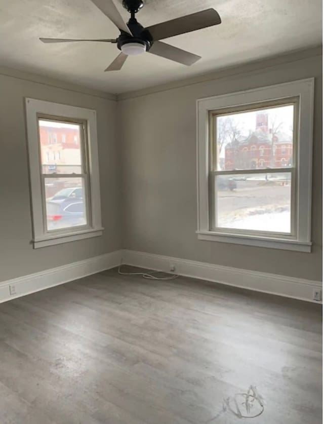 unfurnished room featuring wood-type flooring, crown molding, ceiling fan, and a healthy amount of sunlight