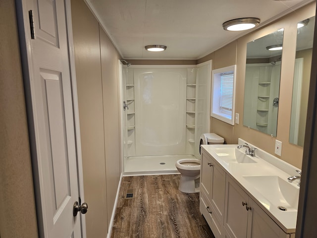 bathroom featuring a shower, wood-type flooring, vanity, and toilet