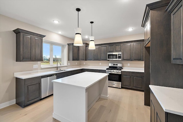 kitchen featuring appliances with stainless steel finishes, sink, light hardwood / wood-style floors, a kitchen island, and hanging light fixtures