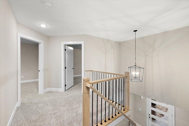 hallway featuring light colored carpet and an inviting chandelier