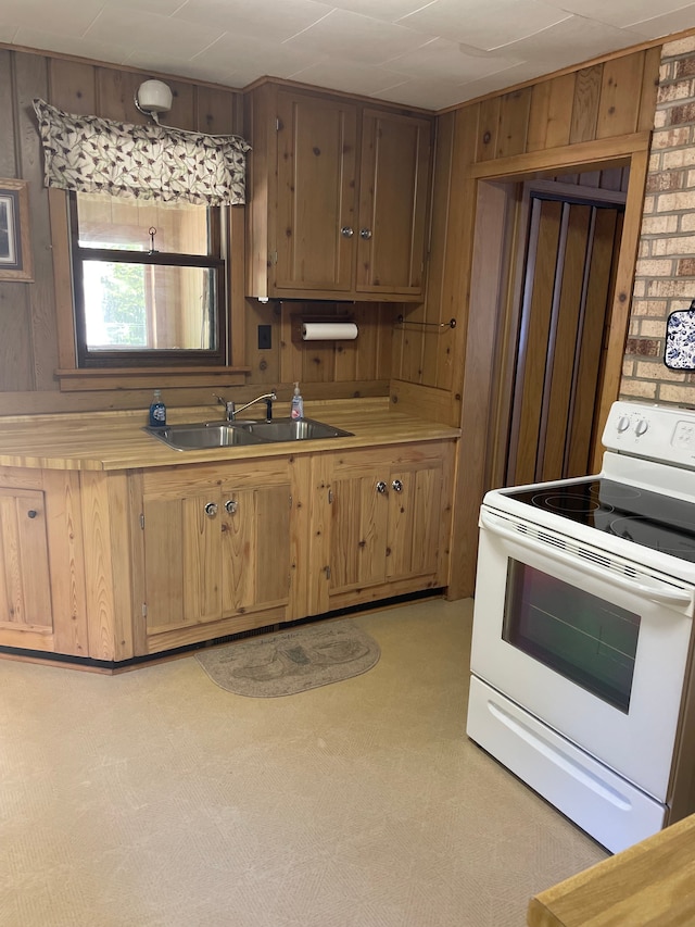 kitchen with wood walls, sink, white electric range oven, and light carpet