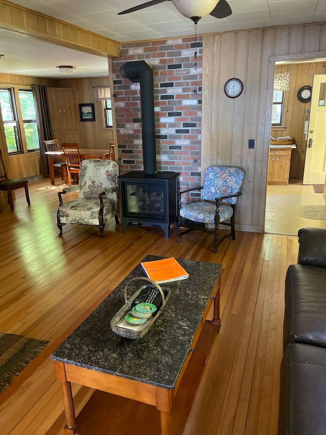 living room featuring a wood stove, wooden walls, and light wood-type flooring