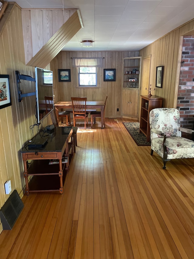 dining room with light wood-type flooring and wooden walls