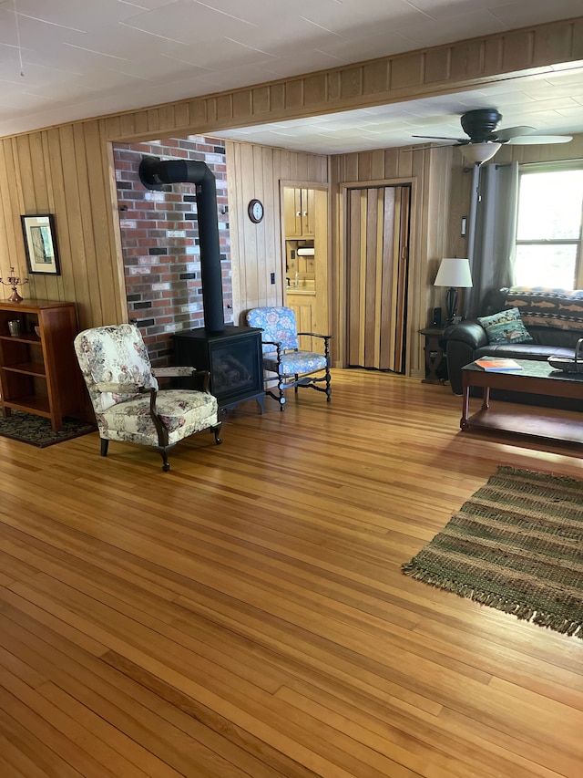 living room featuring a wood stove, wood walls, and hardwood / wood-style floors