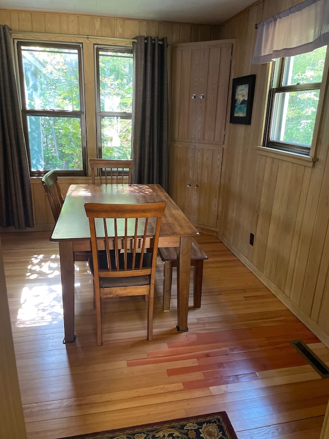 dining space featuring light wood-type flooring and wood walls