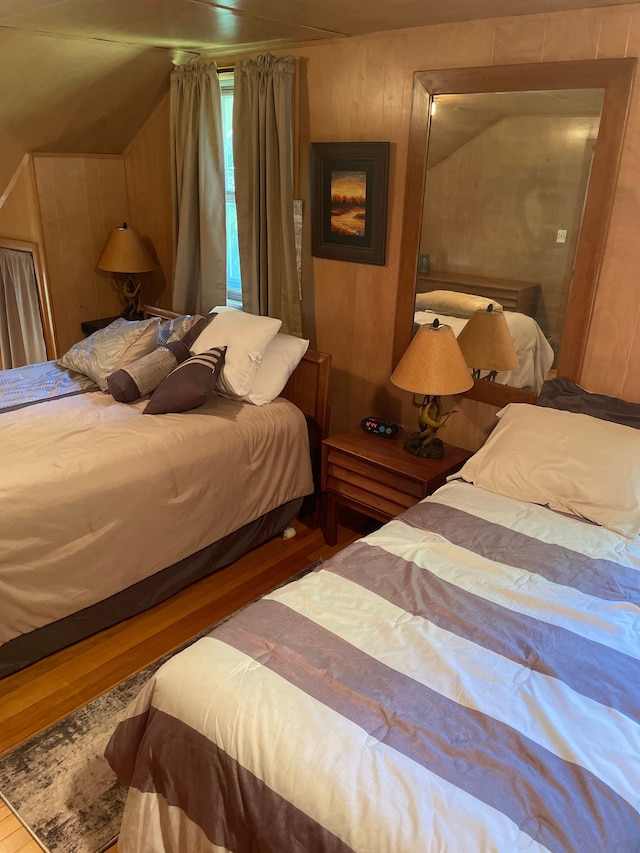 bedroom featuring wood walls, hardwood / wood-style floors, and lofted ceiling