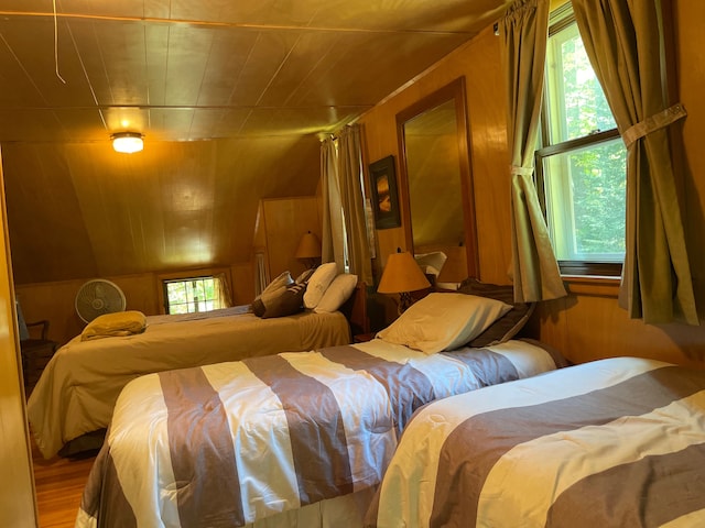 bedroom with wood walls, lofted ceiling, and hardwood / wood-style flooring