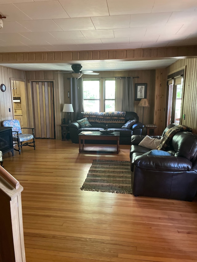 living room with a healthy amount of sunlight, wood-type flooring, and wooden walls