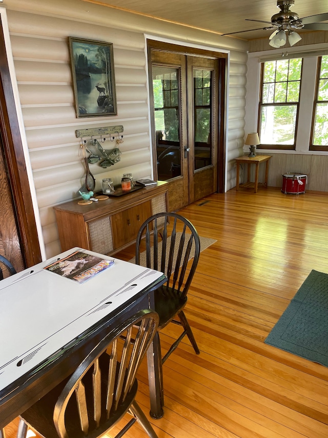 dining area with log walls, light hardwood / wood-style floors, and ceiling fan