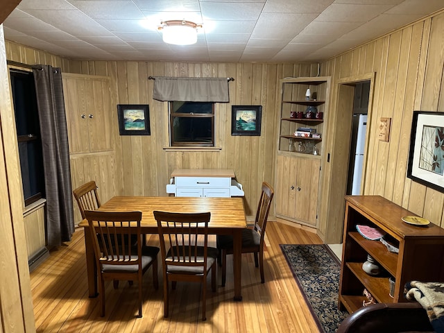 dining room featuring light hardwood / wood-style floors, built in features, and wooden walls