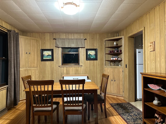 dining room with light wood-type flooring and wooden walls