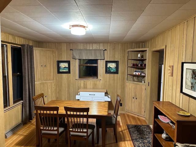 dining space with wood walls and light hardwood / wood-style flooring